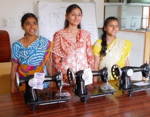 Three Indian women in front of sewing machines