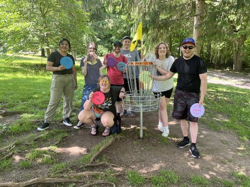 Picture of 7 young men and women having a great time together at a frisbee-golf event. 