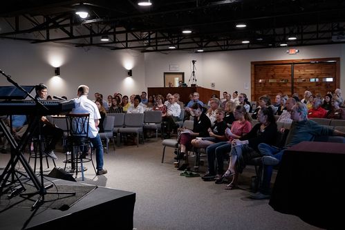 Picture of a church service with the Pastor interviewing a member sharing his testimony with the congregation..