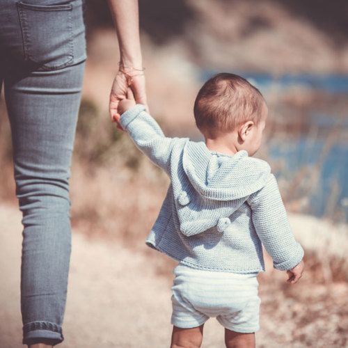 backside view of parent walking a toddler holding hands
