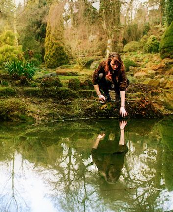 A woman looking at her reflection at a pond
