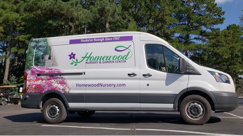 The delivery van for Homewood Nursery parked in the parking lot under the pine trees
